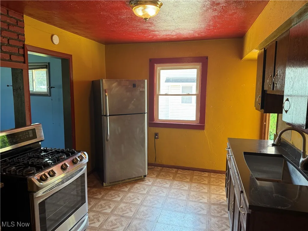 Kitchen with appliances with stainless steel finishes, light floors, and dark countertops