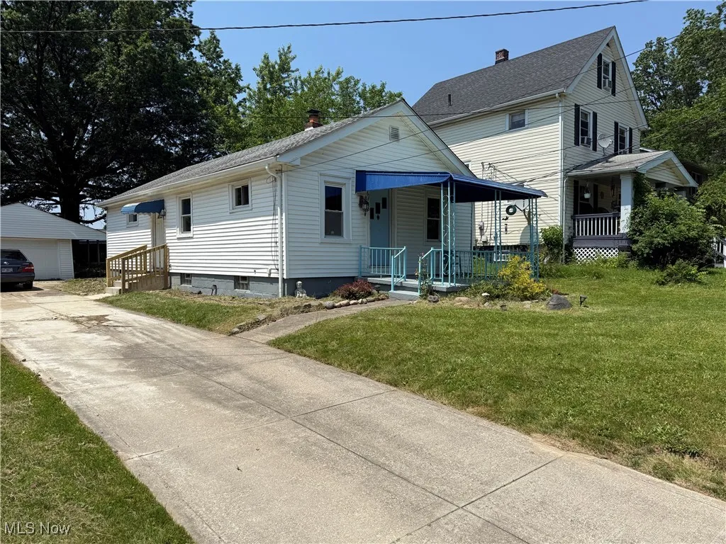 View of front of home featuring a front lawn, an outdoor structure, covered porch, and a chimney
