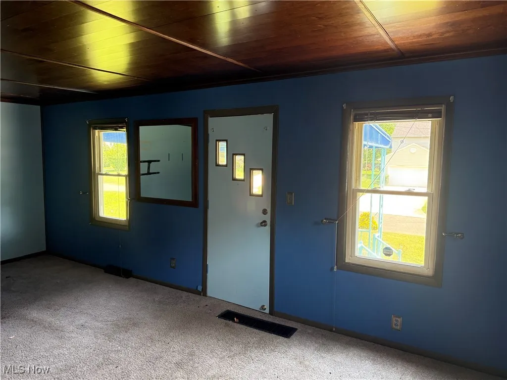 Empty room with wood ceiling, carpet flooring, and healthy amount of natural light