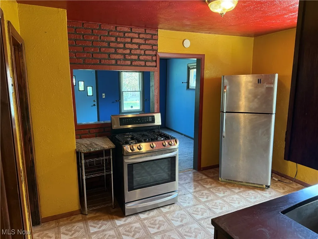Kitchen with appliances with stainless steel finishes, light floors, and a textured ceiling