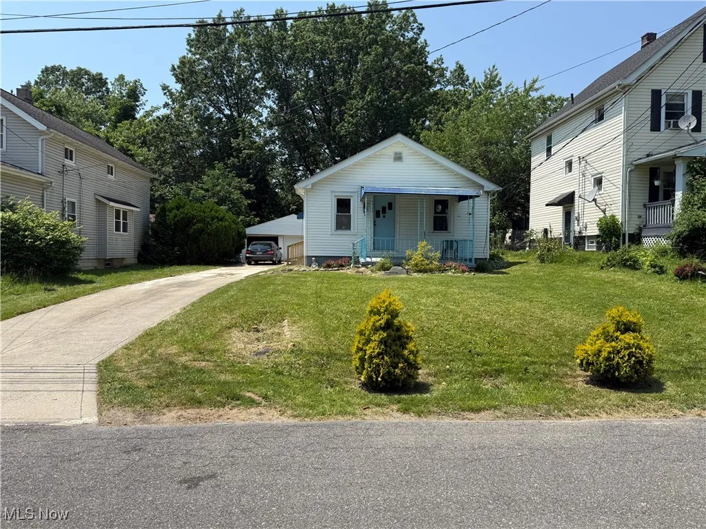 Bungalow-style home with covered porch, a detached garage, and a front yard