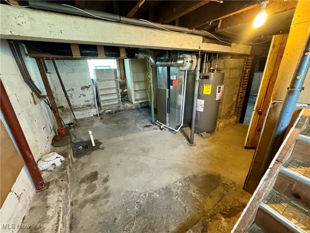 Unfinished below grade area featuring electric water heater and heating unit