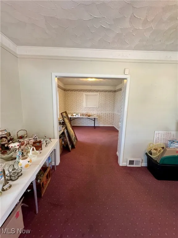 Hallway with wallpapered walls and carpet