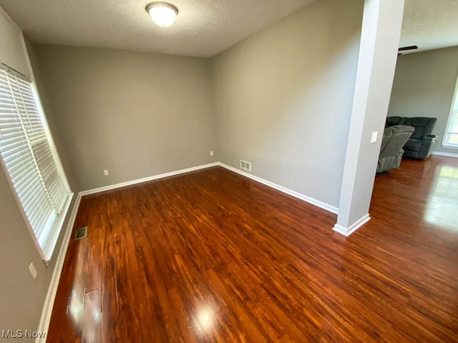 Empty room featuring dark wood-style floors and a textured ceiling