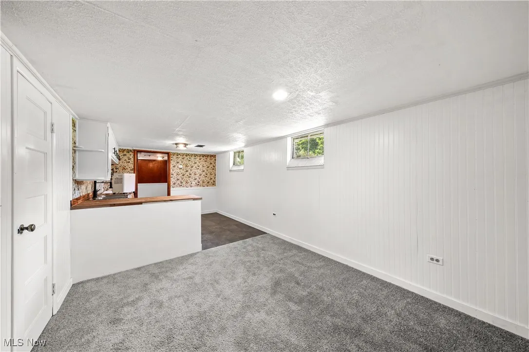 Unfurnished living room with dark carpet and a textured ceiling