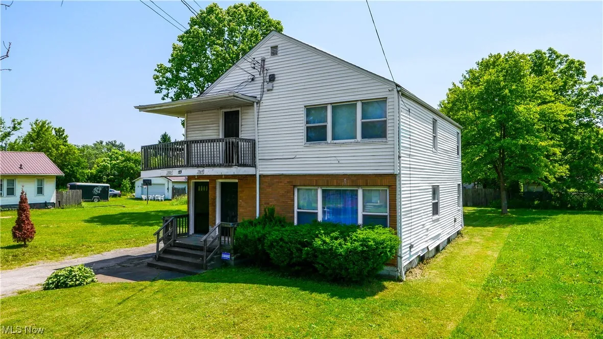 View of front of property with a balcony and a front lawn