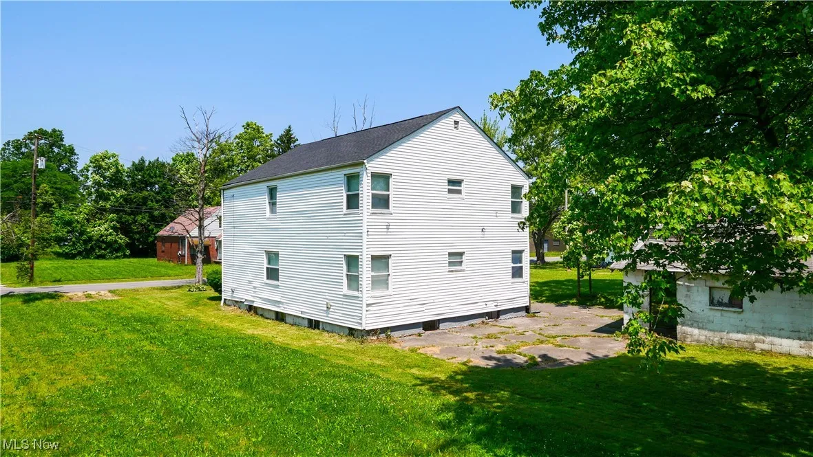 View of side of home with a yard and a shingled roof