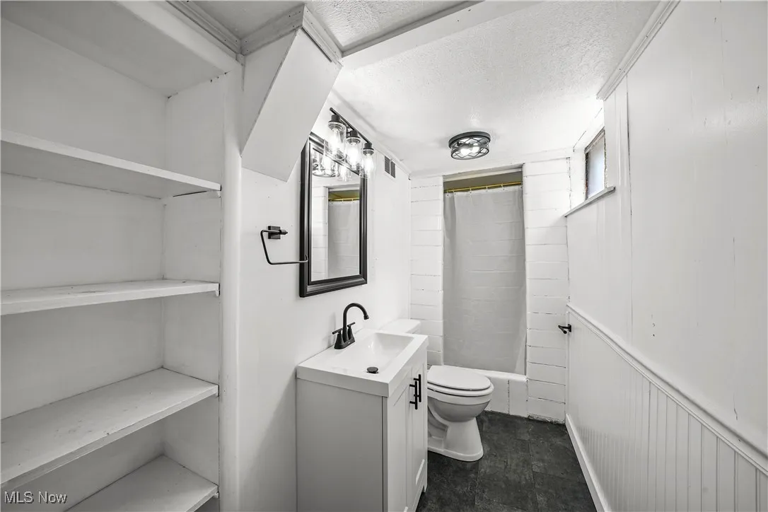 Bathroom with vanity, a textured ceiling, and shower / bath combination with curtain