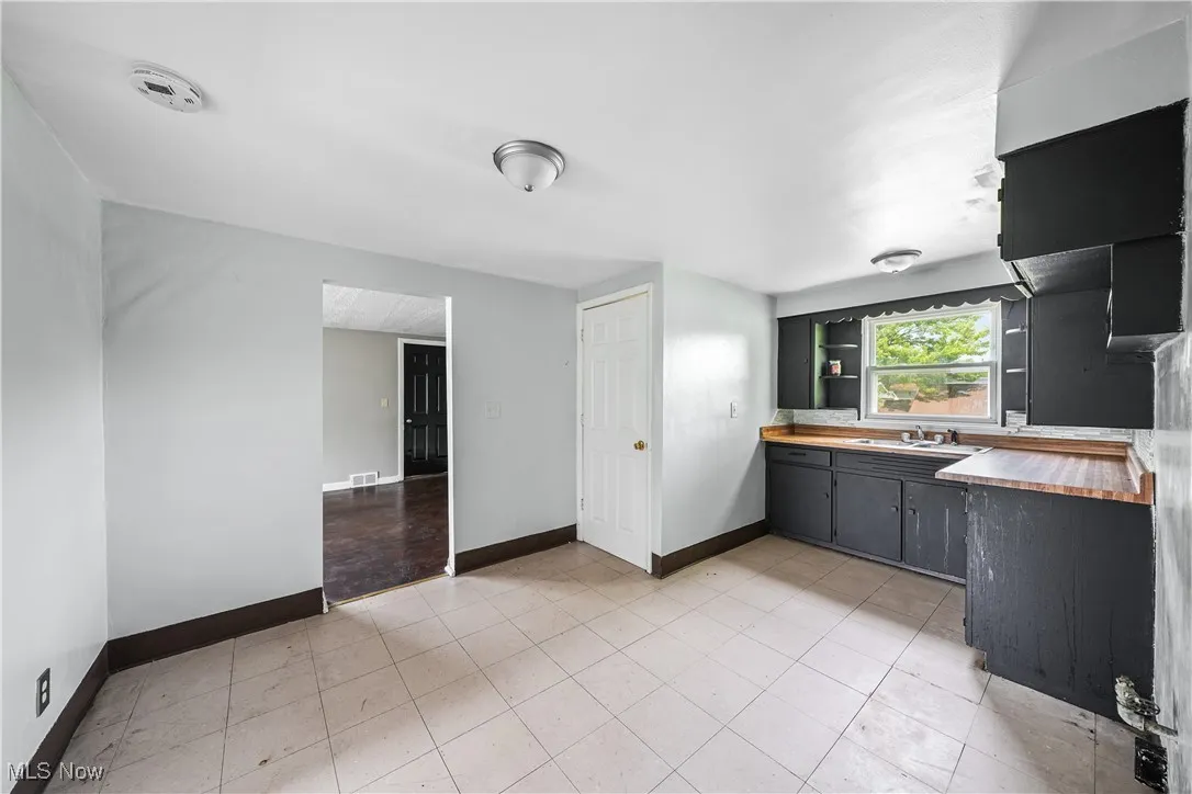 Kitchen with butcher block countertops, open shelves, and light tile patterned floors