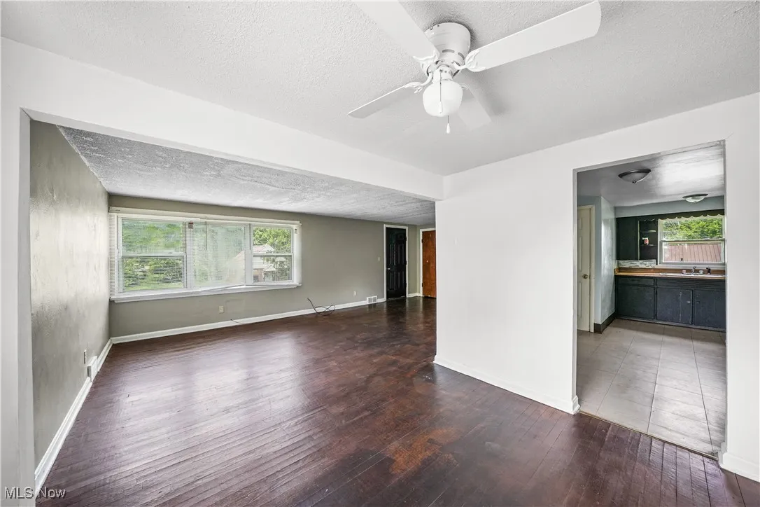 Spare room with hardwood / wood-style floors, plenty of natural light, a textured ceiling, and a ceiling fan