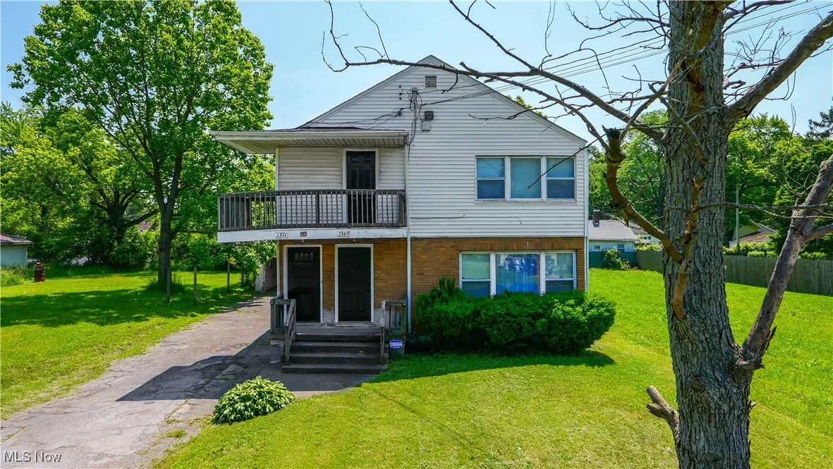 View of front of property with a balcony, asphalt driveway, and brick siding