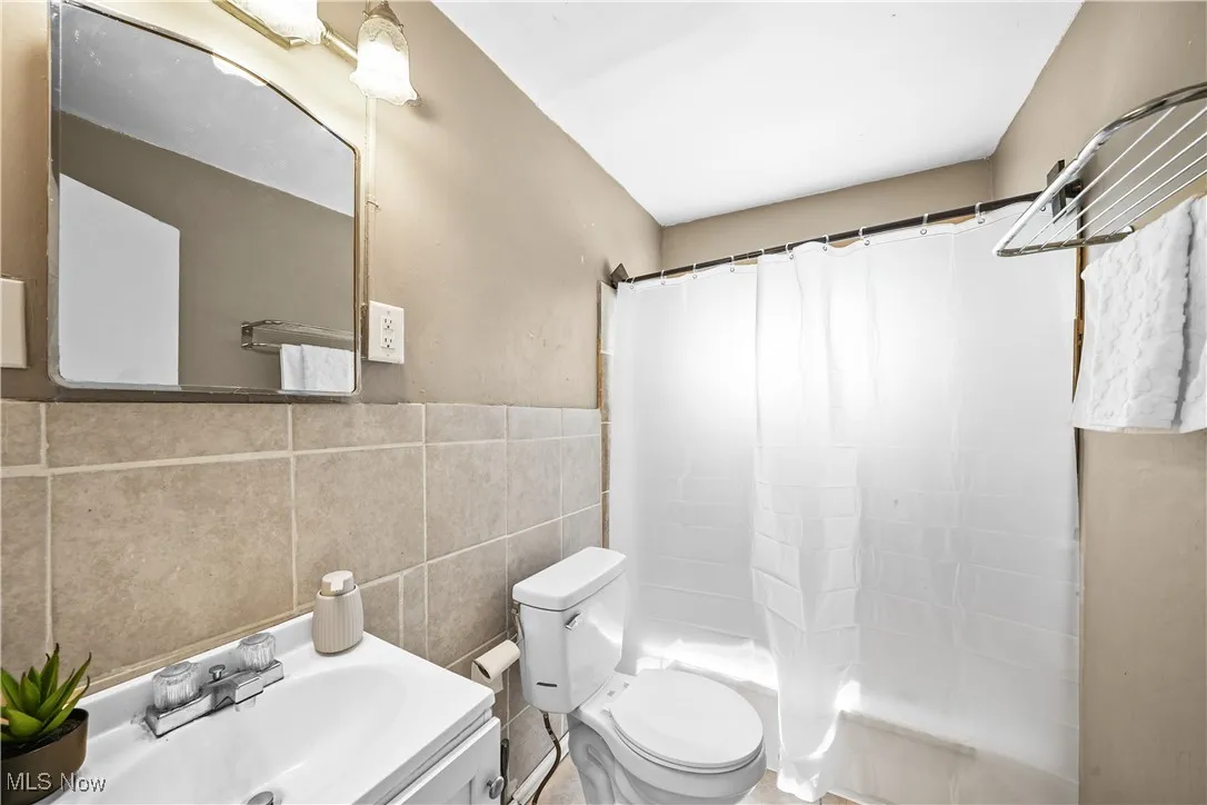 Bathroom with tile walls, vanity, and shower / bathtub combination with curtain