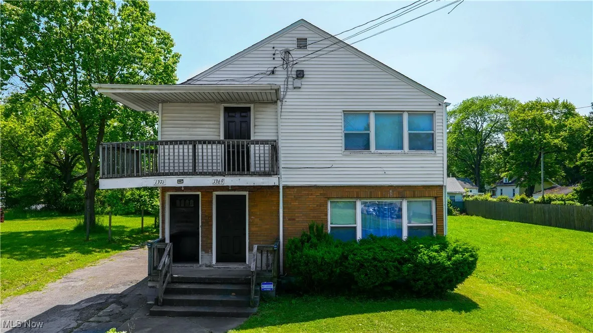 View of front of property with a balcony and a front lawn