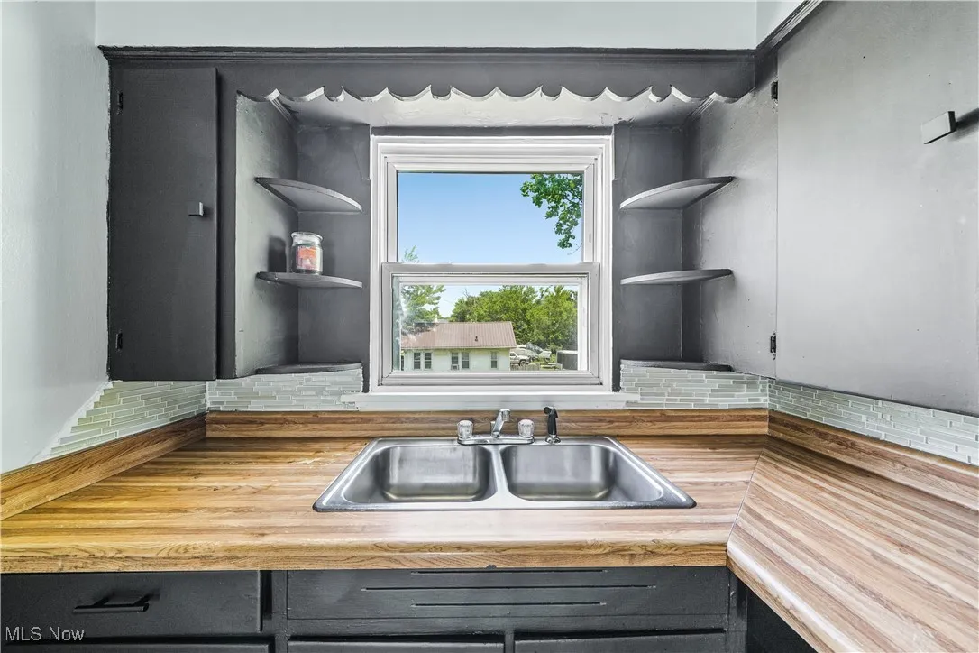 Kitchen with open shelves, backsplash, and wooden counters
