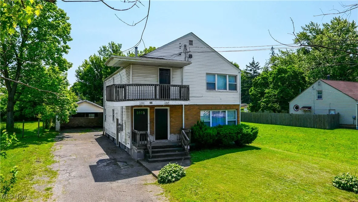 Traditional-style home with a balcony, asphalt driveway, and covered porch