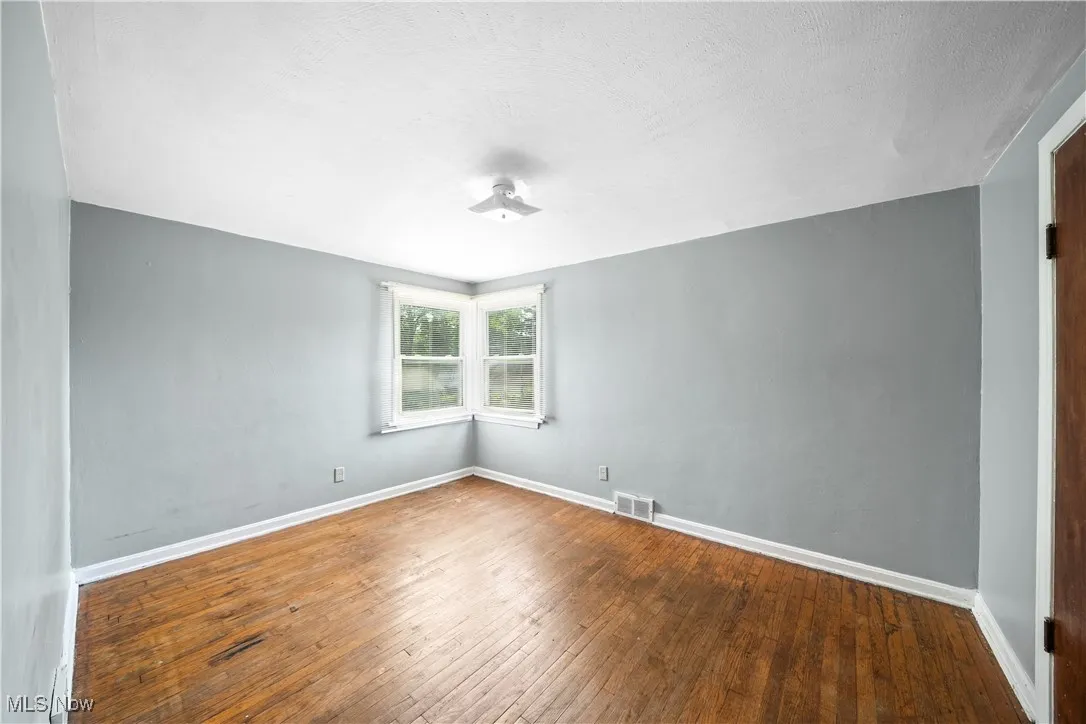 Empty room with baseboards and wood-type flooring