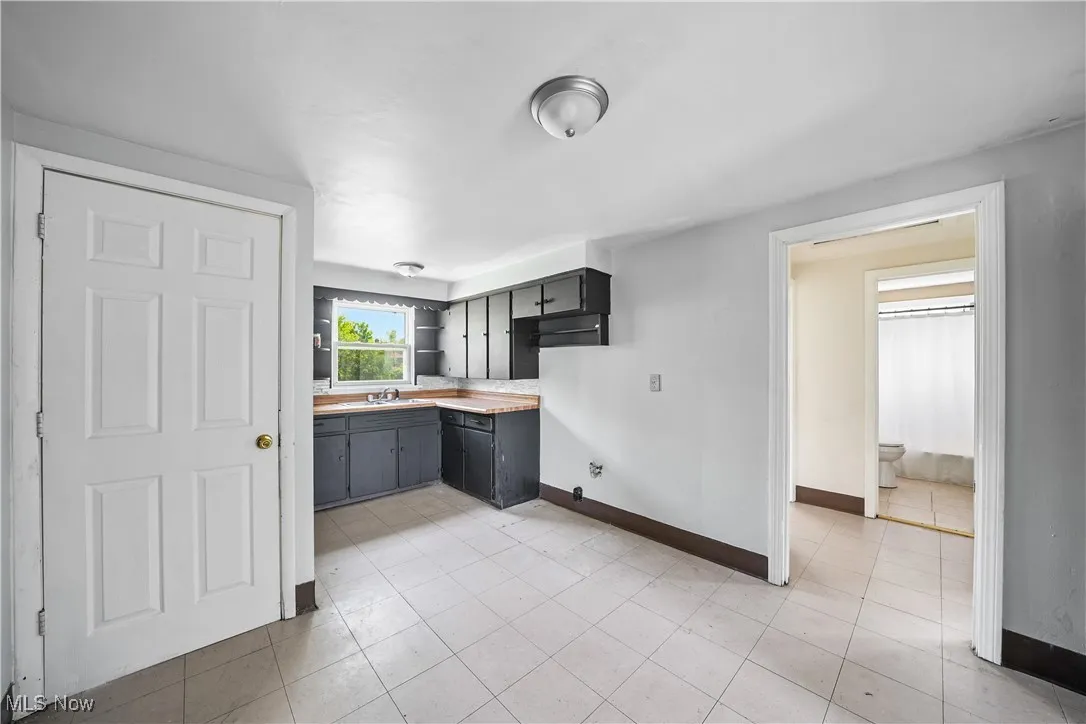 Kitchen with light countertops, open shelves, and light tile patterned floors