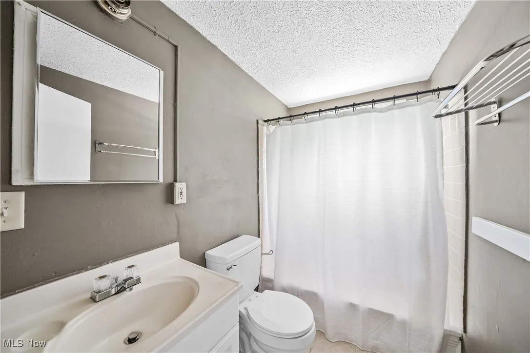 Full bath with shower / tub combo, vanity, and a textured ceiling