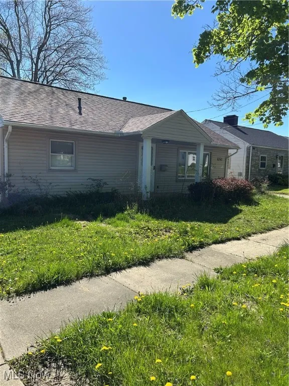 View of side of property with a yard and a shingled roof