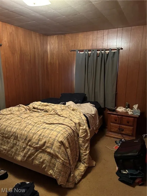 Carpeted bedroom with wood walls