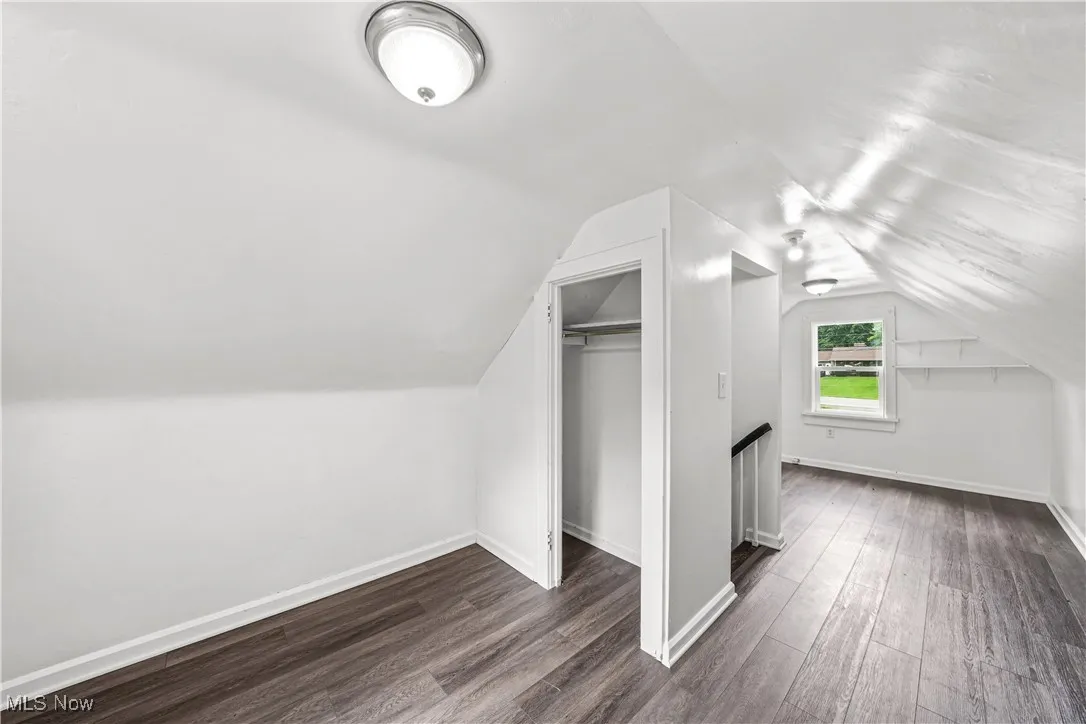Additional living space with dark wood-type flooring and lofted ceiling