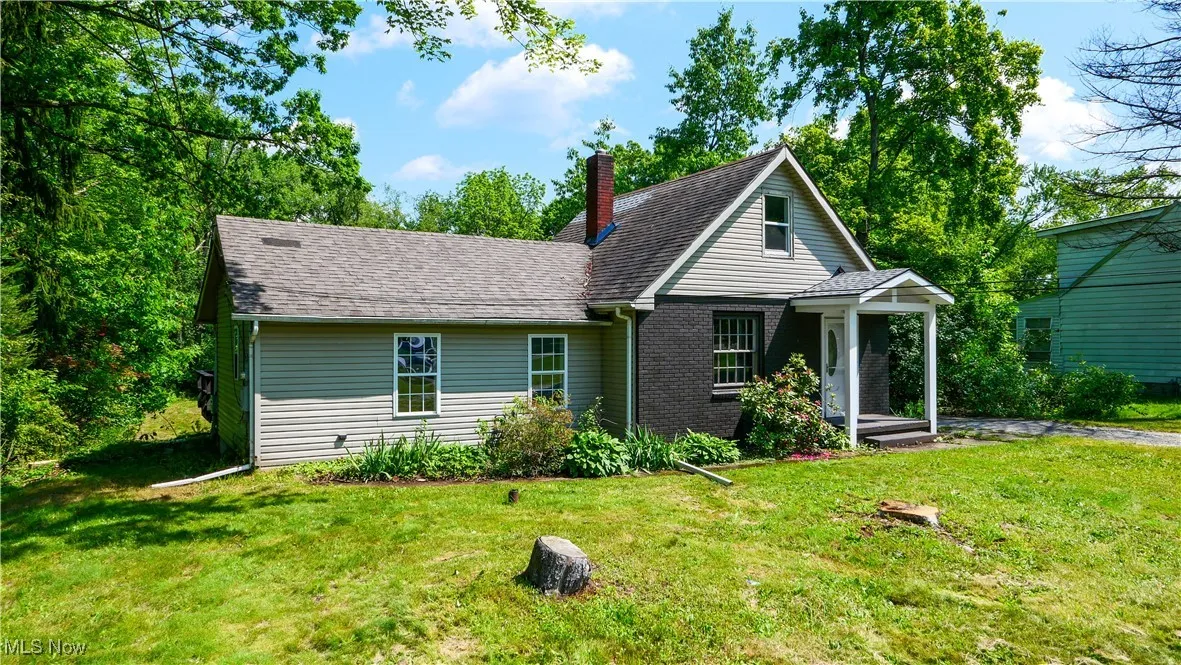View of front of house with a chimney, a front lawn, and roof with shingles