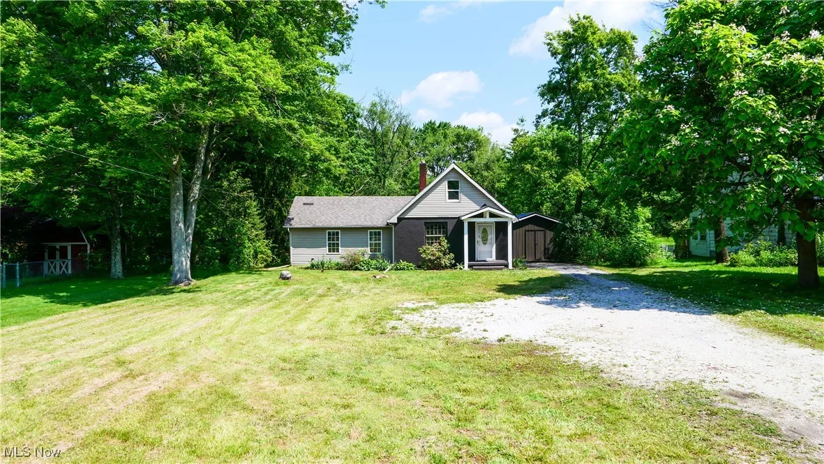 Ranch-style house with gravel driveway, a chimney, and an outdoor structure