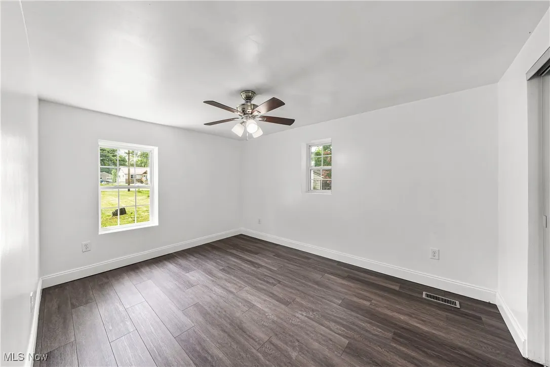 Unfurnished room with plenty of natural light, dark wood finished floors, and ceiling fan