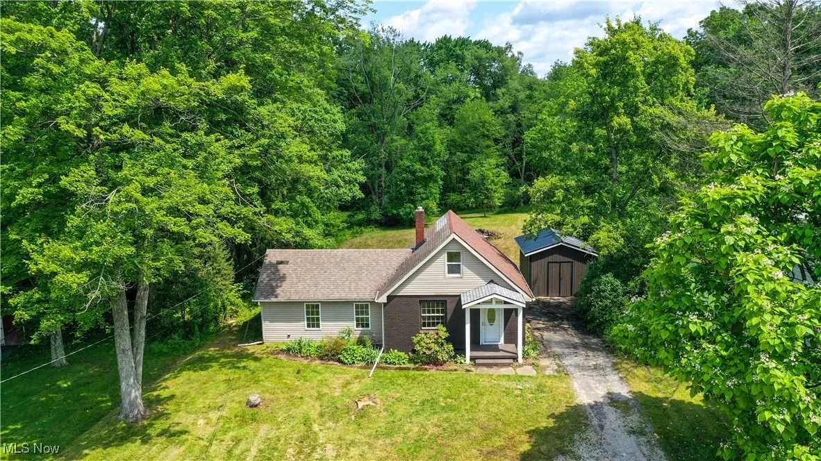 View of front of house featuring a storage shed, a front lawn, and asphalt driveway