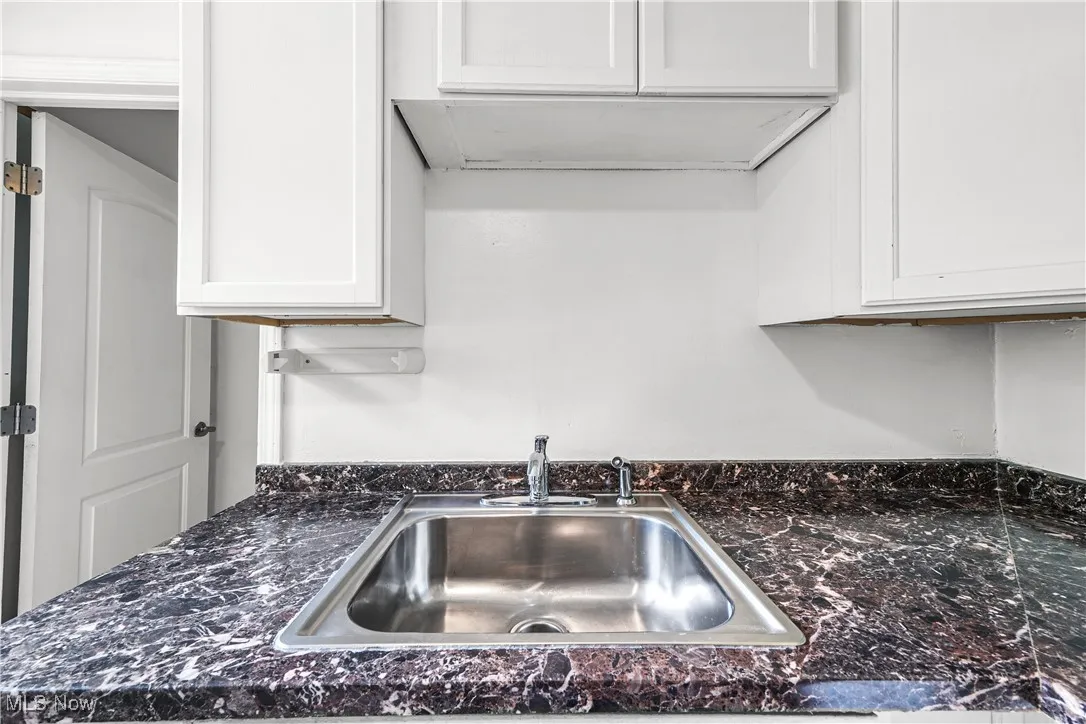 Kitchen featuring dark countertops and white cabinetry