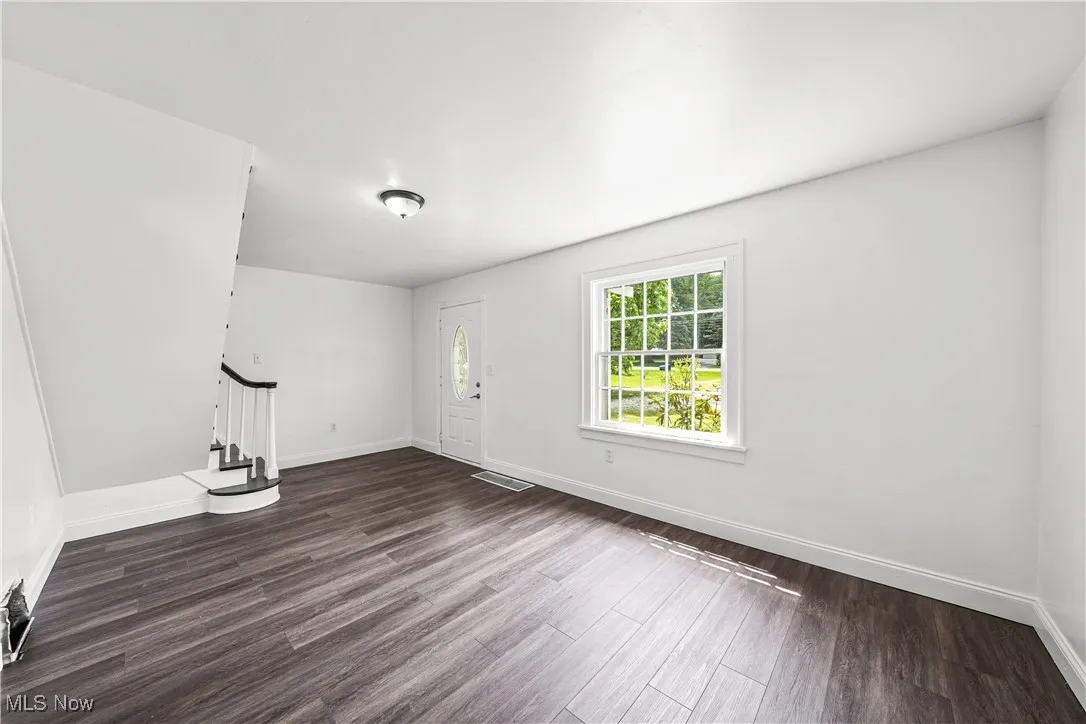Foyer featuring dark wood-style flooring and stairway