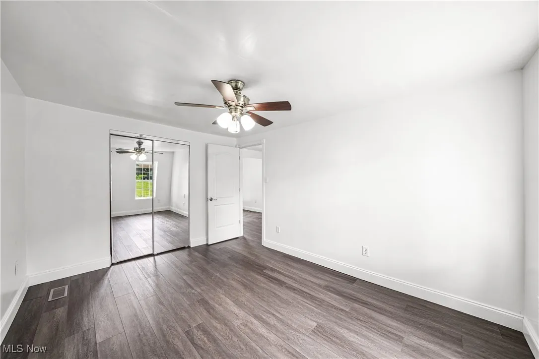 Unfurnished bedroom featuring dark wood-style floors, a closet, and ceiling fan