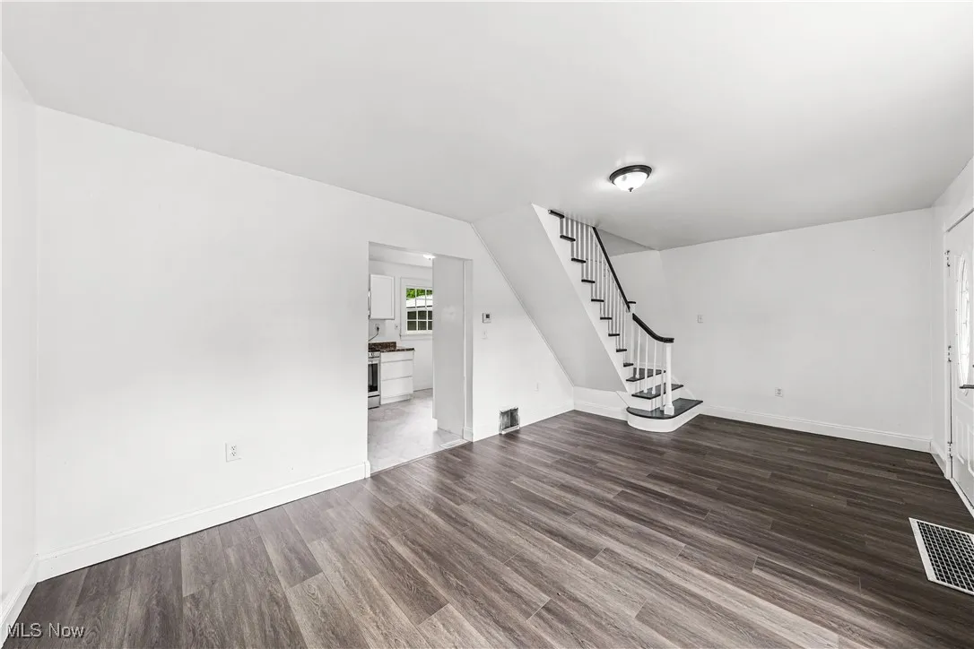 Unfurnished living room featuring stairs and wood finished floors
