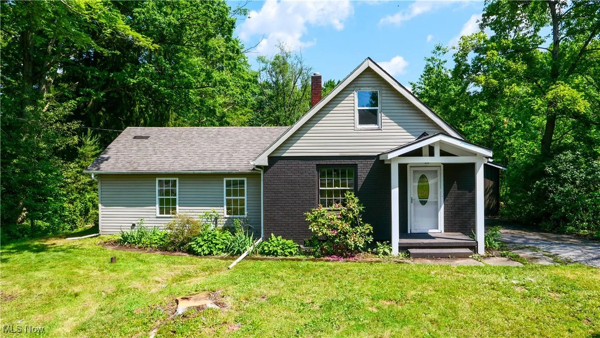 View of front of property featuring a chimney, a front yard, and a shingled roof