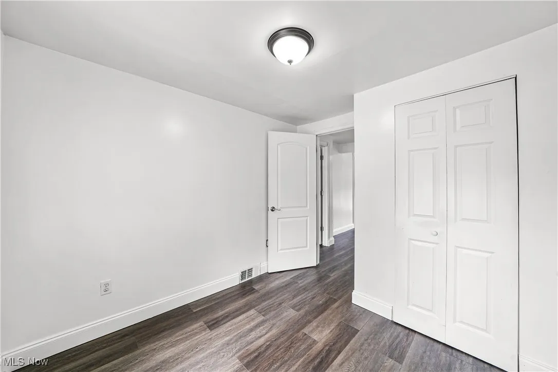 Unfurnished bedroom with dark wood-type flooring and a closet