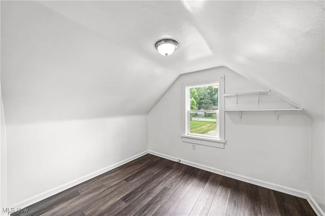 Bonus room featuring dark wood finished floors and vaulted ceiling