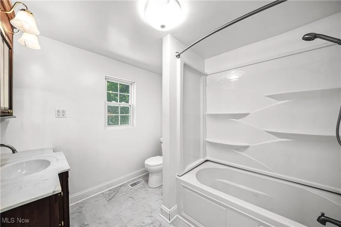 Bathroom featuring marble finish floors, vanity, and shower / washtub combination