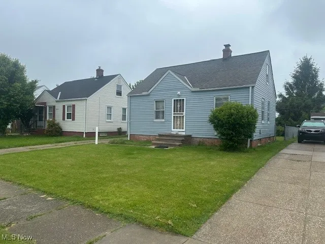 View of front of home with a front lawn, concrete driveway, a chimney, and a shingled roof