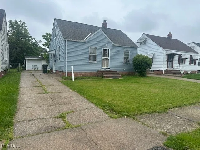 Bungalow-style house featuring a front yard, roof with shingles, and a detached garage