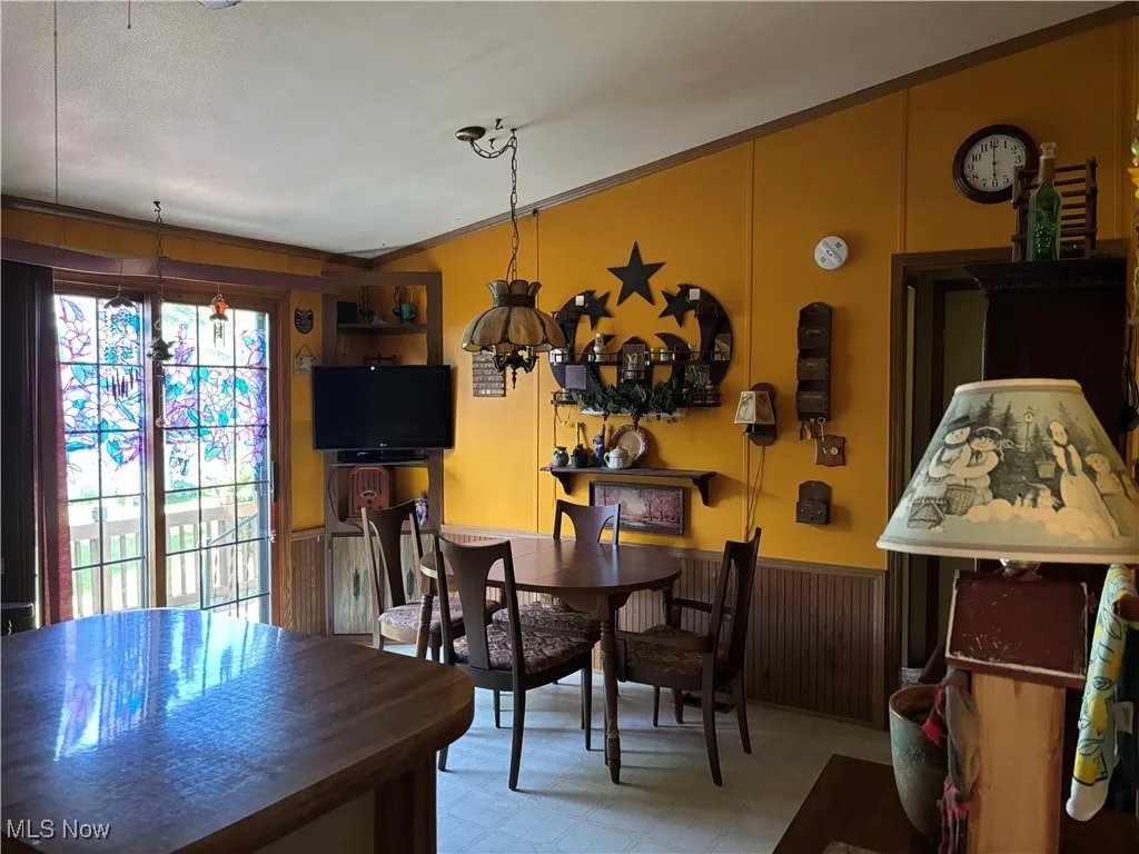Dining space with vaulted ceiling, light flooring, and ornamental molding
