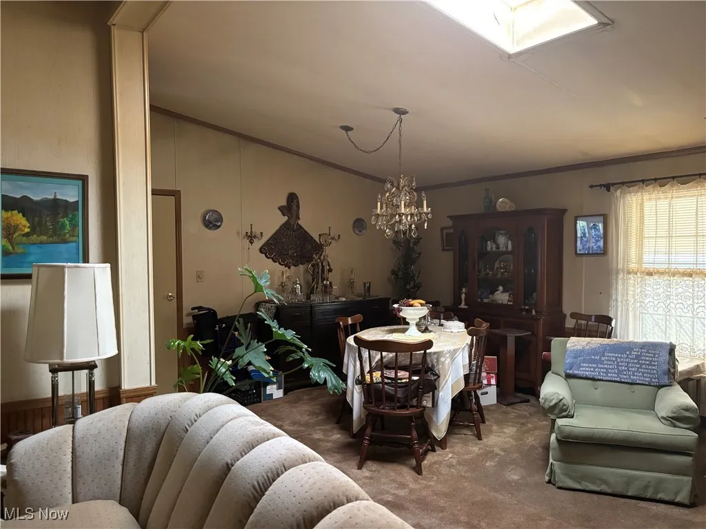 Dining space with carpet floors, lofted ceiling, a chandelier, and crown molding