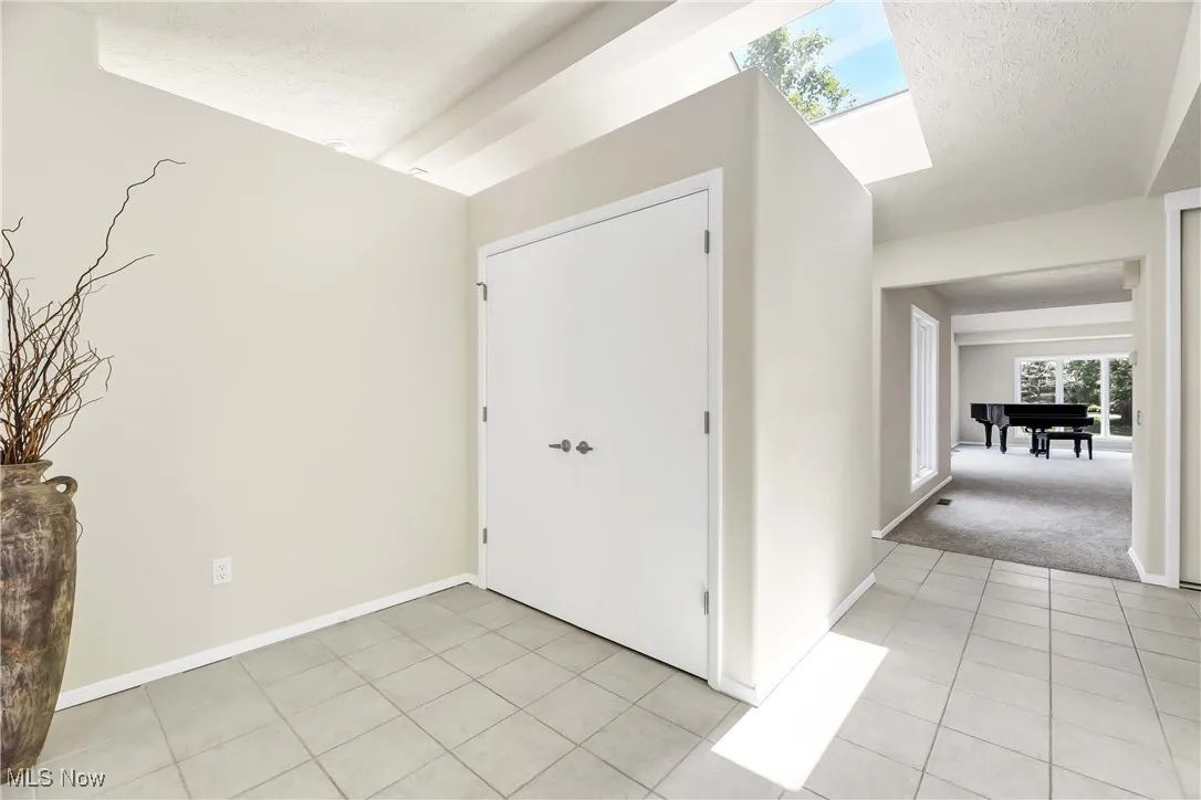 Foyer entrance featuring light tile patterned floors, a textured ceiling and a skylight