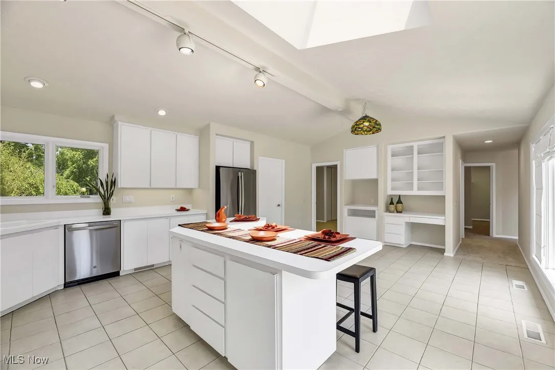 Kitchen featuring appliances with stainless steel finishes, light tile patterned flooring, a breakfast bar, light countertops, and vaulted ceiling