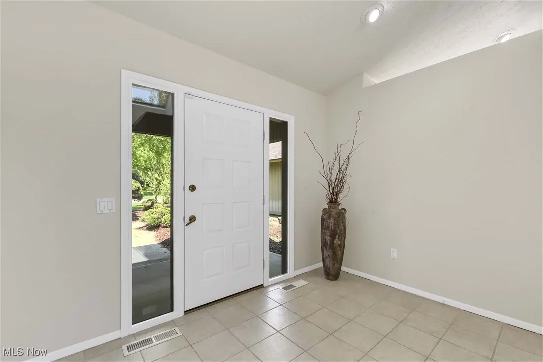Entryway featuring lofted ceiling and light tile patterned flooring
