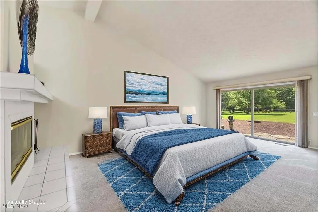 Bedroom with access to exterior, vaulted ceiling, a glass covered fireplace, and carpet
