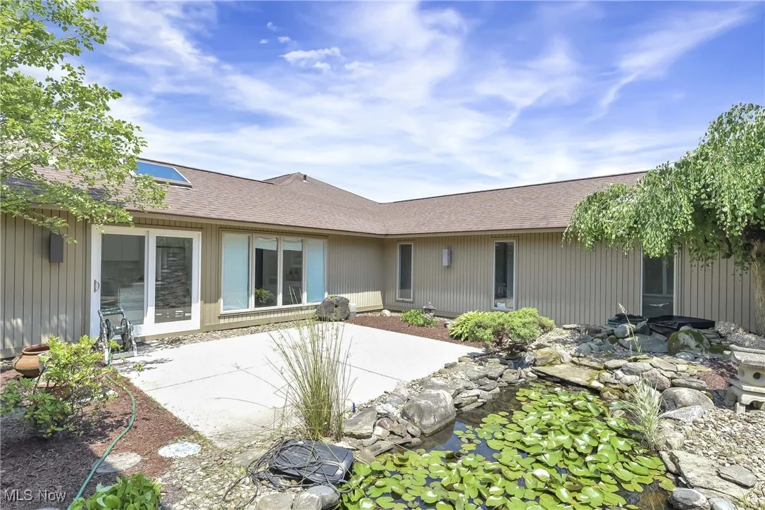 Back of house with a shingled roof and a patio