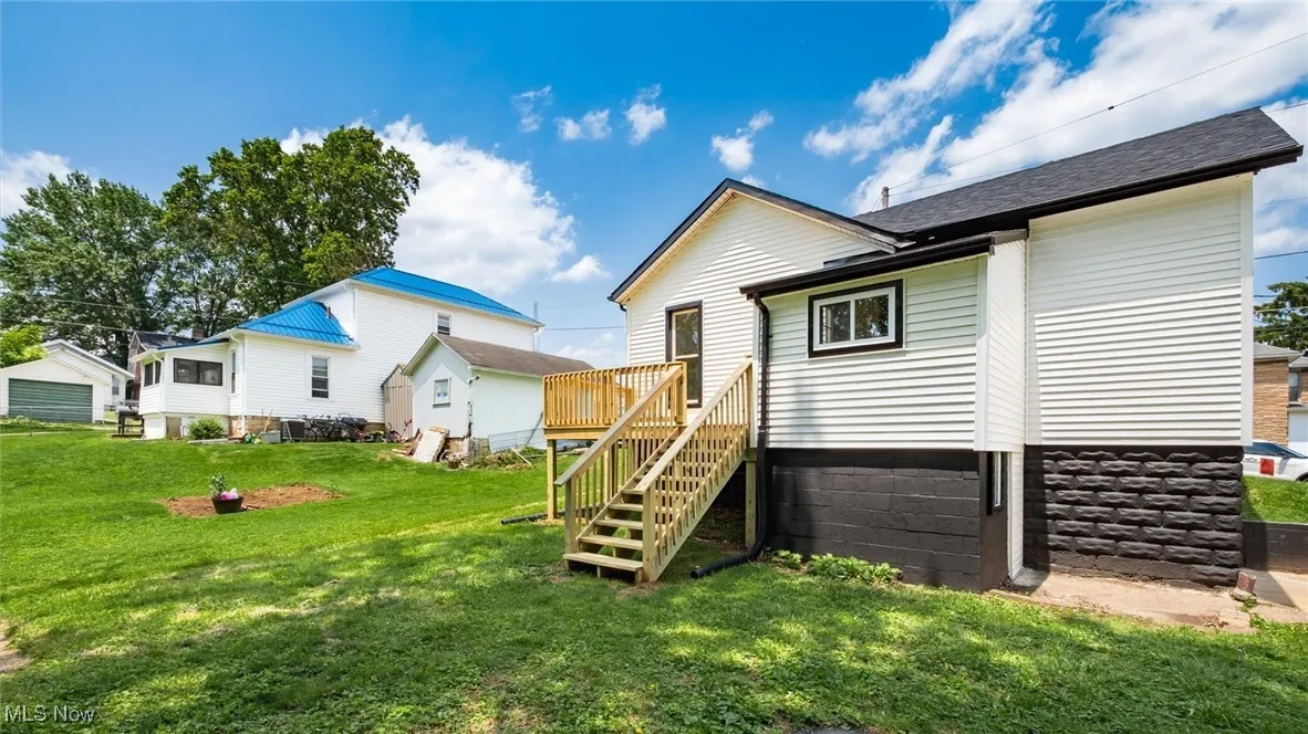 Back of property featuring a yard, stairs, and a deck