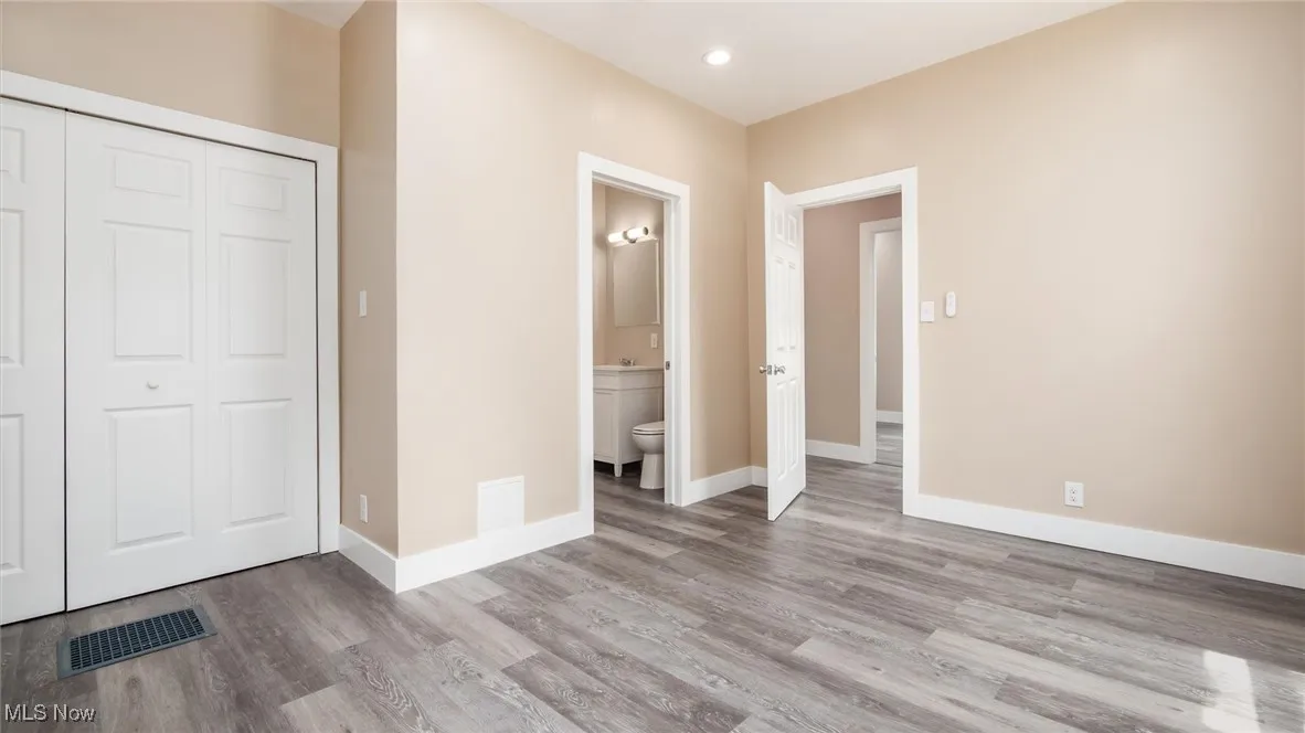 Unfurnished bedroom with wood finished floors, a closet, connected bathroom, and recessed lighting