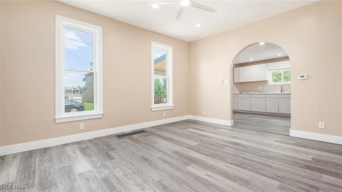 Empty room featuring a ceiling fan, light wood-style flooring, recessed lighting, and arched walkways