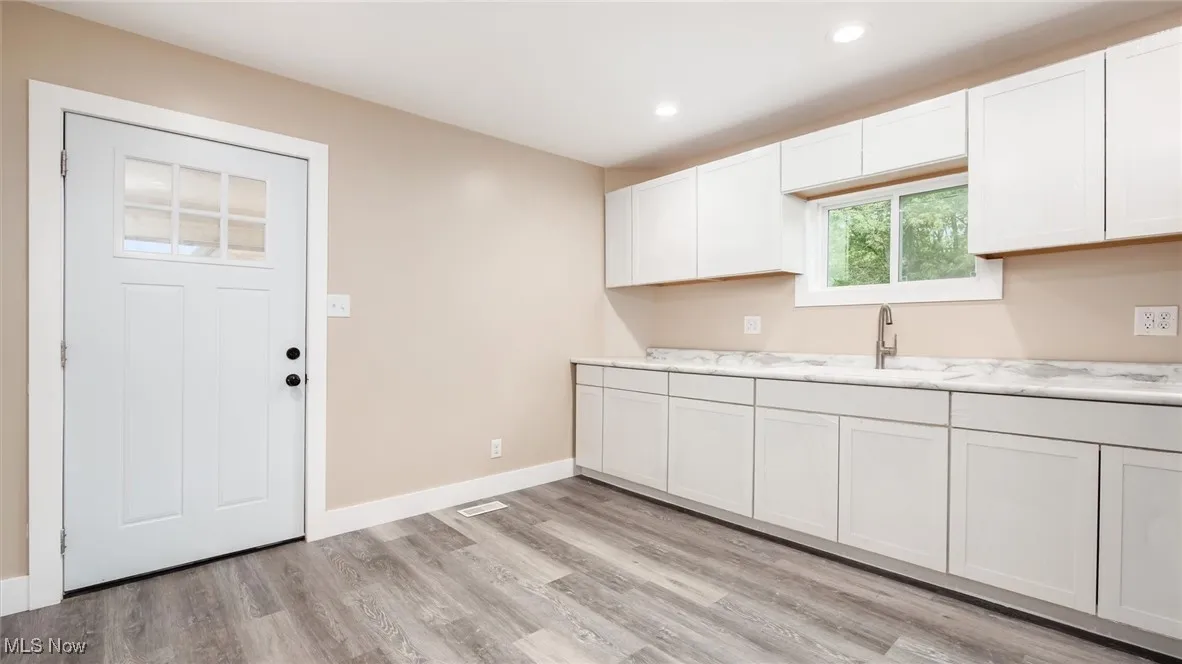 Kitchen with light wood-style floors, recessed lighting, and white cabinets